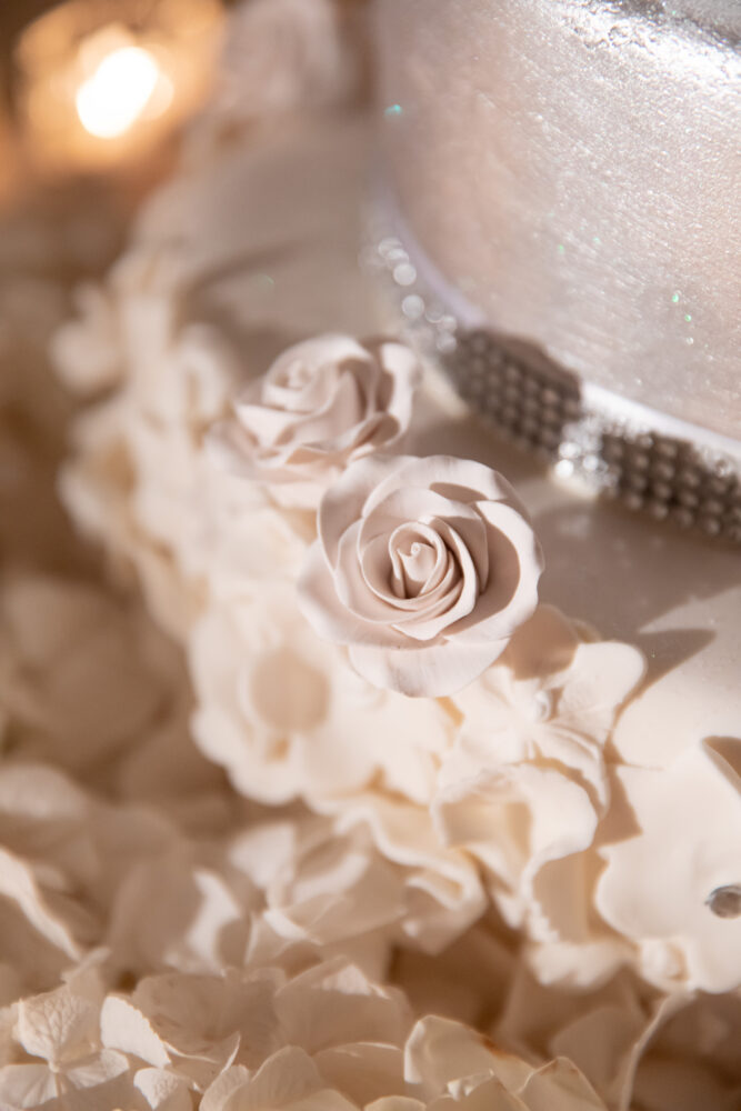 up close shot of a wedding cake with roses and diamond details