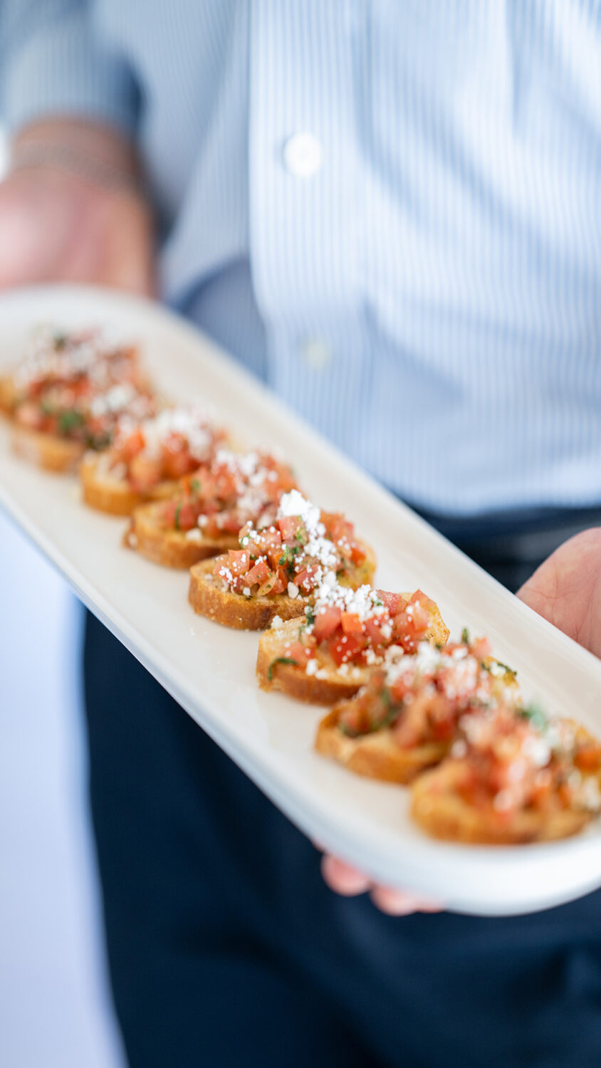 server holding a platter of toasties with tomatoes and cheese on top