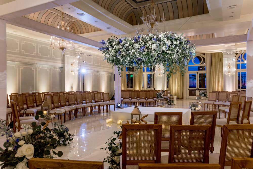 wedding reception setup in the ballroom with flowers hanging from the ceiling