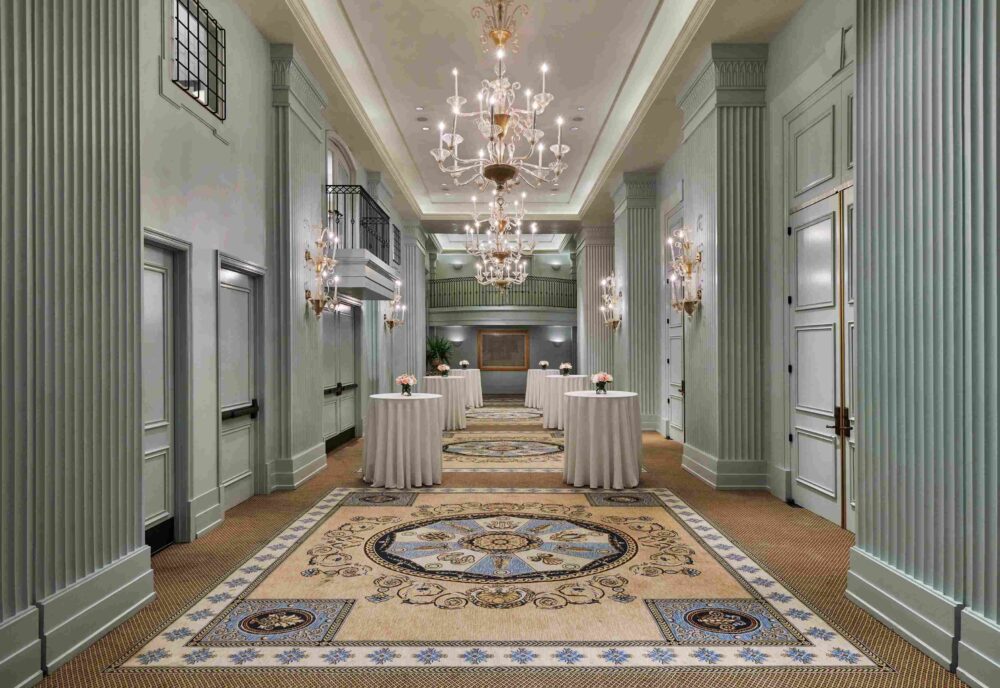 Colonnade Foyer event space with teal walls and beautiful, crystal chandeliers
