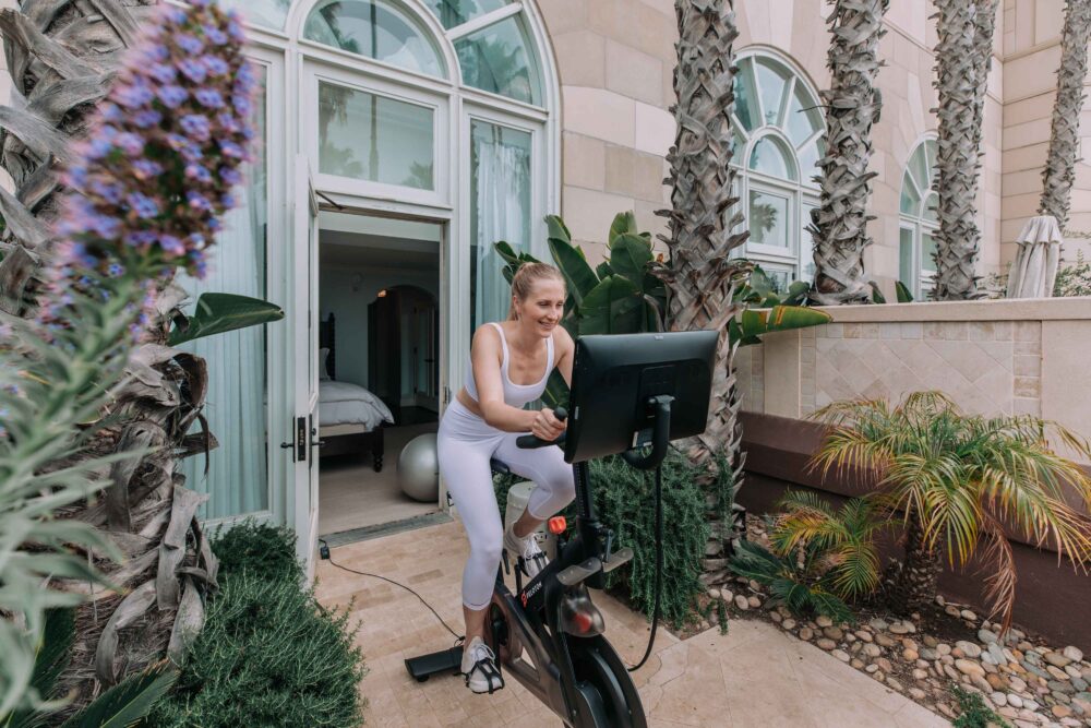 woman on a peloton bike outside on the balcony of her room