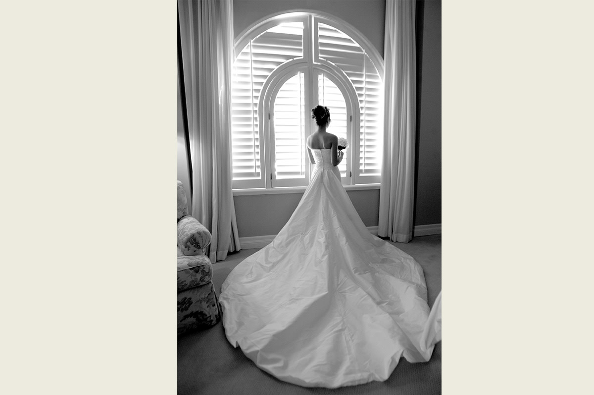 black and white image of the back of the bride's dress near the window